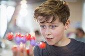 Curious boy examining molecule model in laboratory classroom