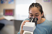 Girl student using microscope in classroom