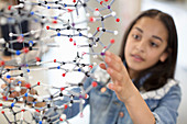 Girl student examining molecular structure in classroom