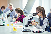 Student using microscop conducting scientific experiment
