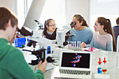 Students using microscope, conducting scientific experiment