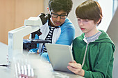 Students using tablet at microscope in laboratory classroom