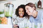 Mother and daughter making healthy green smoothie