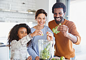 Multi-ethnic family making green smoothie in kitchen