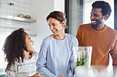 Multi-ethnic family making healthy green smoothie in kitchen