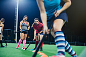 Female field hockey players practicing sports drill on field