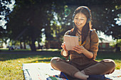 Woman using a tablet, listening to music with headphones