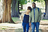 Young couple holding hands, walking in park