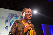 Smiling female speaker with microphone on stage