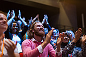 Smiling, enthusiastic man clapping in audience