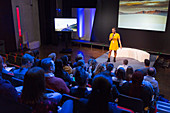 Female speaker on stage talking to audience