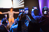 Audience with camera phones photographing speaker on stage