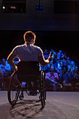 Female speaker with microphone in wheelchair on stage