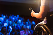 Female speaker in wheelchair holding microphone on stage