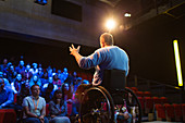 Audience watching male speaker in wheelchair talking
