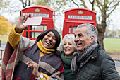 Friends taking selfie in front of red telephone booths