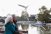 Affectionate senior couple watching birds flying at river