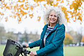 Smiling senior woman bike riding in autumn park