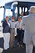 Active senior friend tourists standing outside tour bus
