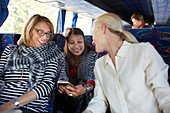 Senior women tourist friends using smart phone on tour bus