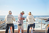 Senior tourists on bicycles looking at sunny ocean view