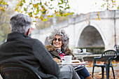 Senior couple enjoying coffee at autumn park cafe