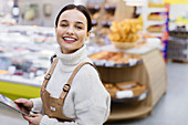 Female grocer with digital tablet working in supermarket