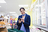 Woman with smart phone shopping in supermarket