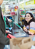 Female cashier helping customer at supermarket checkout