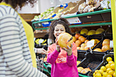 Smiling daughter showing grapefruit to mother in supermarket