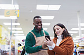 Grocer helping customer with smart phone in supermarket