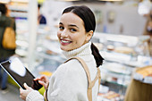 Female grocer with digital tablet working in supermarket