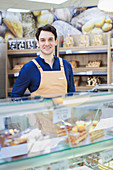 Confident man working at bakery display case in supermarket