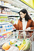 Woman reading label on container in supermarket