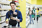 Father with baby scanning label on box in supermarket