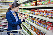 Woman reading label on jar in supermarket
