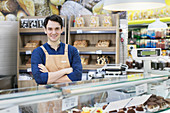 Male worker behind bakery display case in supermarket