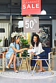 Women with digital tablet shopping in home decor shop