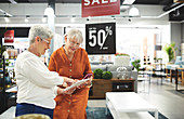 Senior women with digital tablet shopping in home decor shop