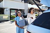 Women loading shopping bags into back of car