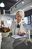 Senior woman with digital tablet working in home decor shop