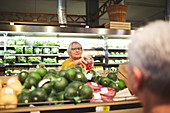 Woman shopping for tomatoes in supermarket produce section