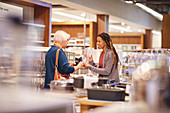 Female worker helping senior woman shopping in home store