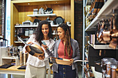 Smiling women with smart phone shopping for frying pans