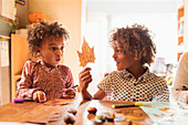 Brother and sister making autumn crafts at table