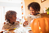 Brother and sister making autumn crafts at table