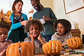 Portrait happy boy carving pumpkins with family