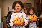Portrait happy brother and sister holding pumpkins
