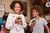 Happy brother and sister with decorated Halloween cupcakes
