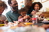 Multiethnic family decorating cupcakes at table